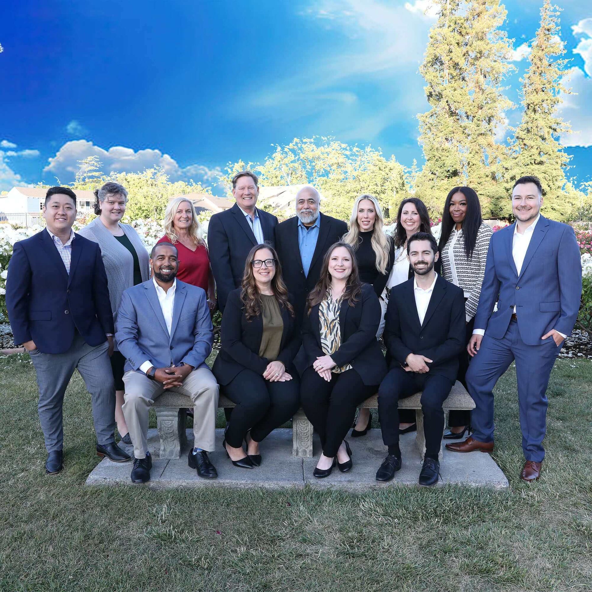 Diverse team of professionals posing outdoors under a bright blue sky, showcasing unity and collaboration.