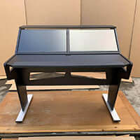 Modern black and white studio desk with two screen mounts on a wooden floor.